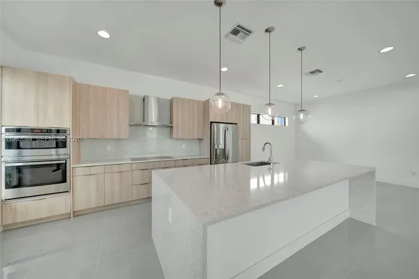 a large kitchen with stainless steel appliances granite countertop a sink a stove and a refrigerator