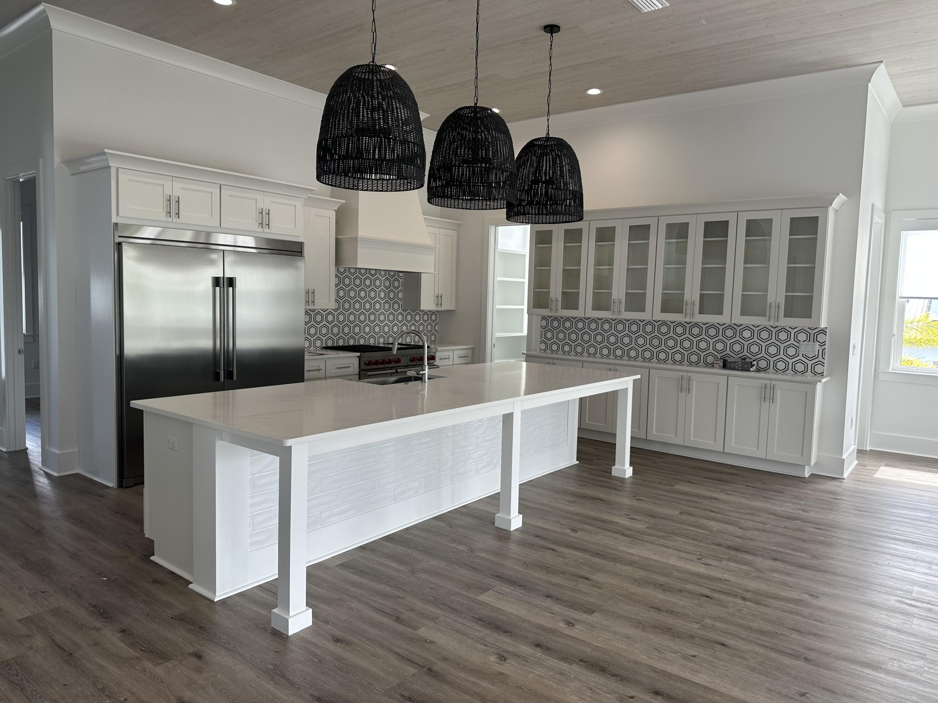141 Maple Street Santa Rosa Beach, FL 32459 - Photo 3 of 11 a kitchen with stainless steel appliances kitchen island granite countertop a stove a refrigerator a dining table and chairs with wooden floor