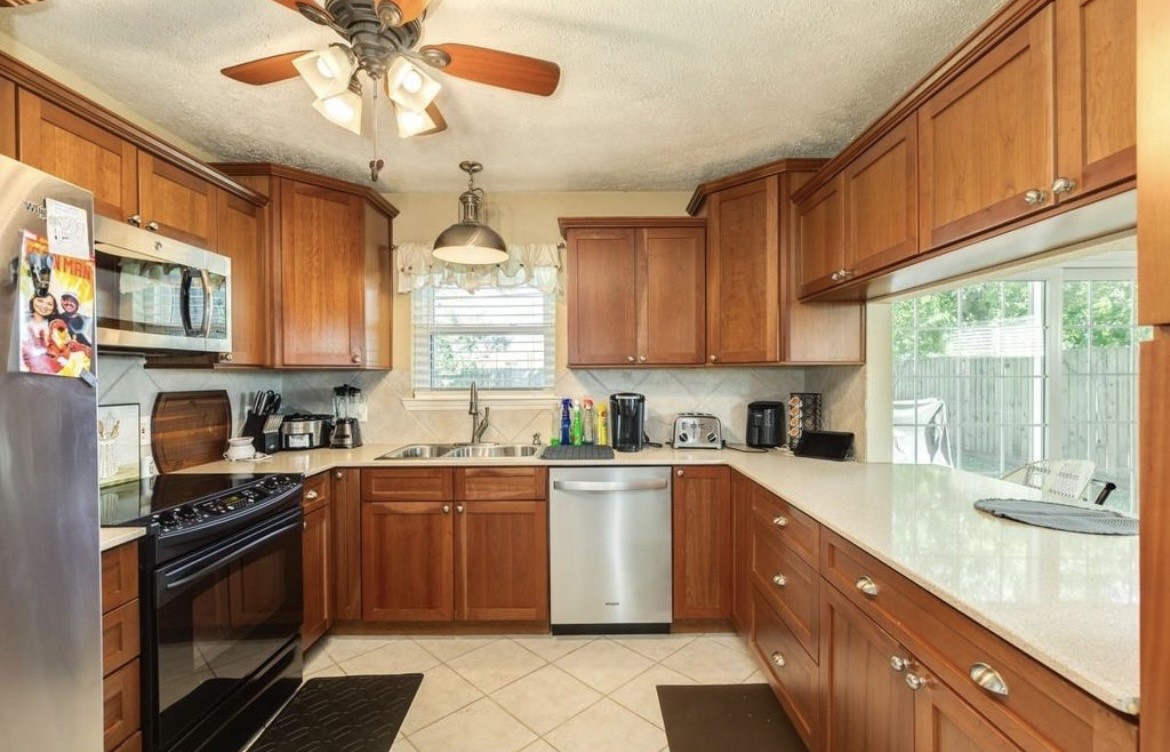 820 Perry Street Angleton, TX 77515 - Photo 17 of 26 a kitchen with stainless steel appliances granite countertop a sink a stove top oven a chimney cabinets and a window