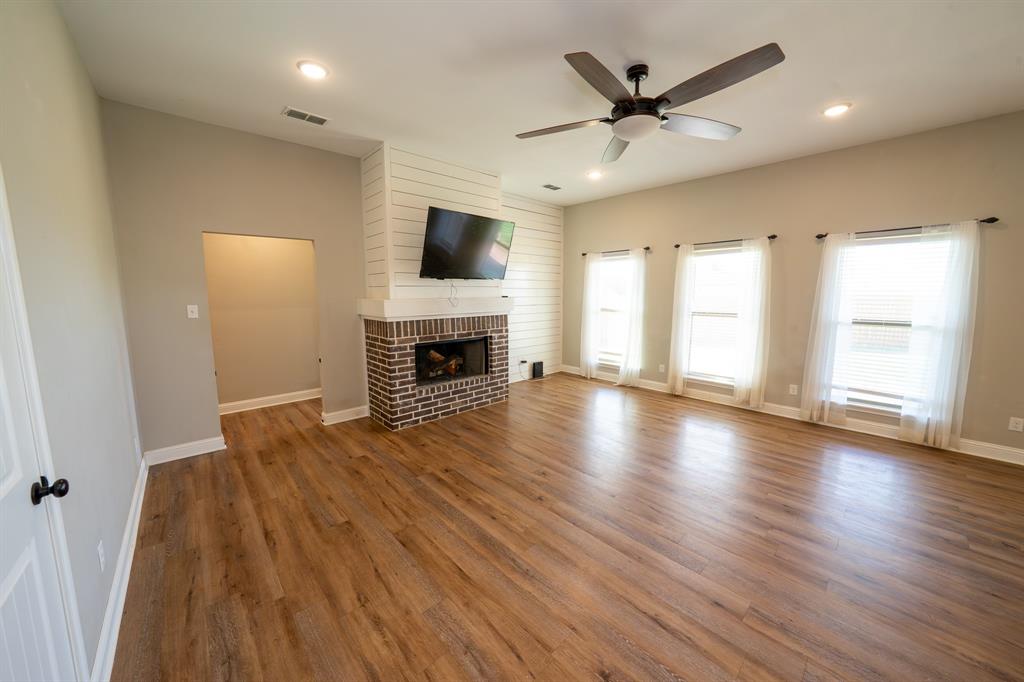 132 Addie Way Tuscola, TX 79562 - Photo 4 of 37 an empty room with windows a fireplace and a ceiling fan