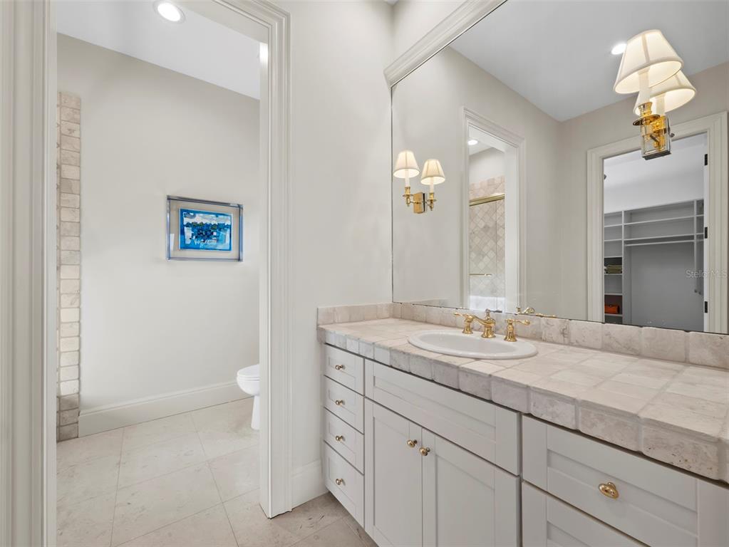 65 Lighthouse Point Drive Longboat Key, FL 34228 - Photo 57 of 90 a bathroom with a granite countertop sink a toilet and a mirror