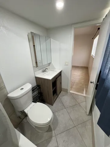 a white toilet sitting next to a bathroom sink and a mirror