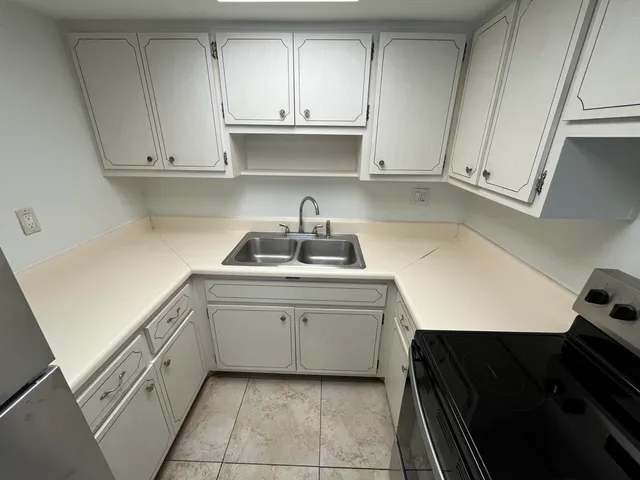 a kitchen with white cabinets and sink
