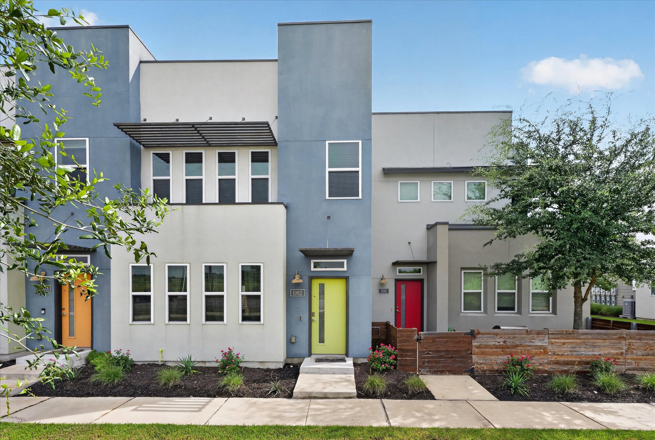 9015 Cattle Baron Path, Unit 1102 Austin, TX 78747 - Photo 2 of 25 Modern townhomes showcasing vibrant entry doors and clean-lined architectural details.