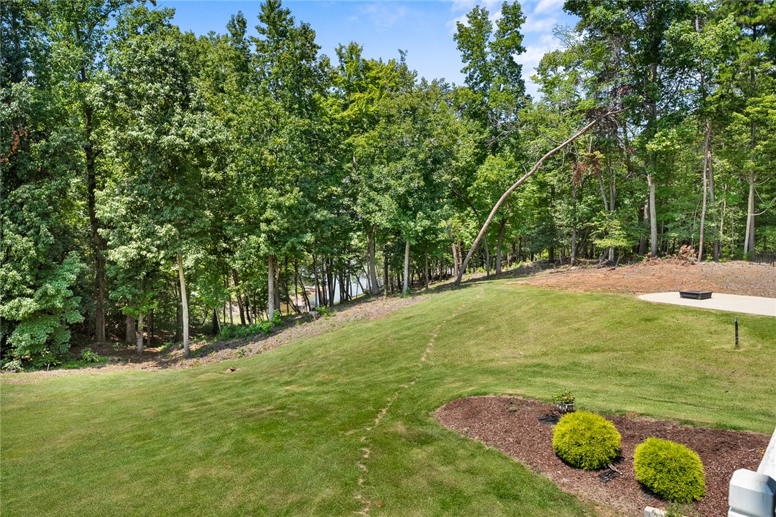 206 James Hare Road Anderson, SC 29626 - Photo 44 of 50 A verdant backyard with mature trees slopes gently towards a serene lake.