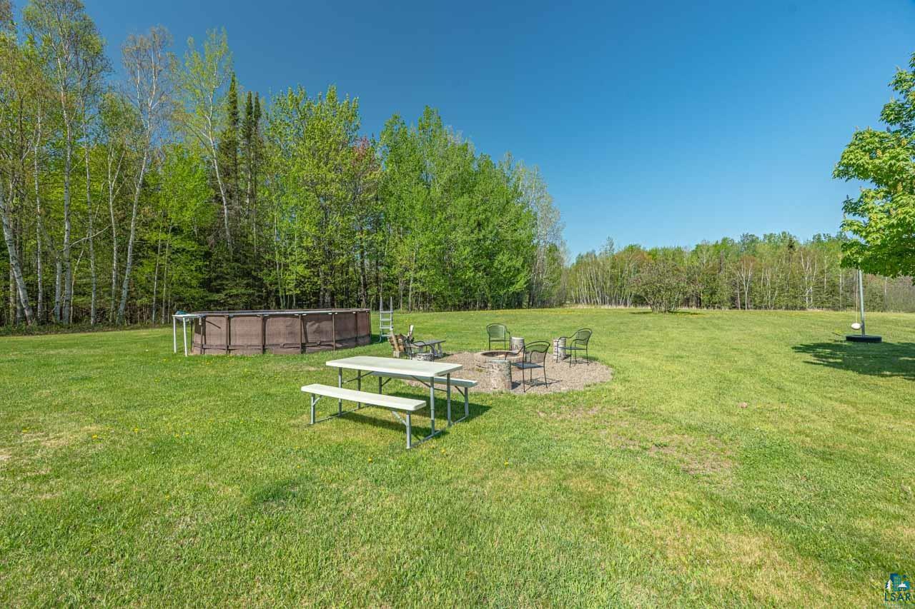 2581 O'Rourke Road Hibbing, MN 55746 - Photo 34 of 61 Expansive green lawn featuring a fire pit area, an above-ground swimming pool, and a backdrop of mature trees