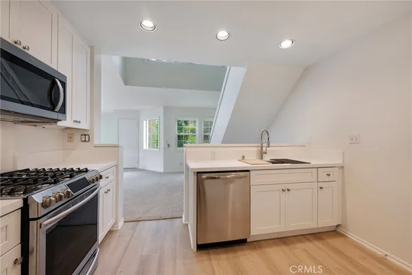 a kitchen with stainless steel appliances a sink cabinets and wooden floor