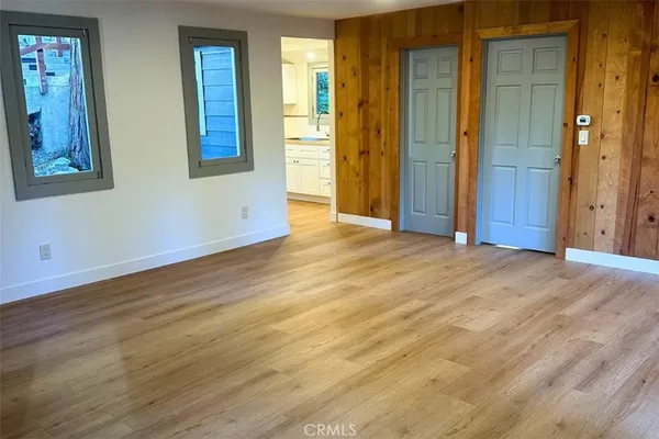 a view of an empty room with wooden floor and a bathroom