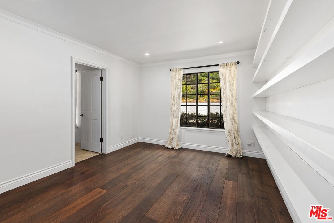 1060 Chantilly Road Los Angeles, CA 90077 - Photo 20 of 40 a view of an empty room with wooden floor and a window