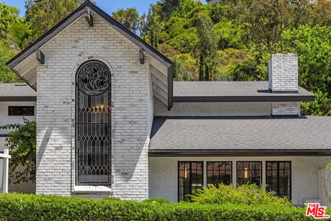 1060 Chantilly Road Los Angeles, CA 90077 - Photo 2 of 40 a view of a house with brick walls and potted plants
