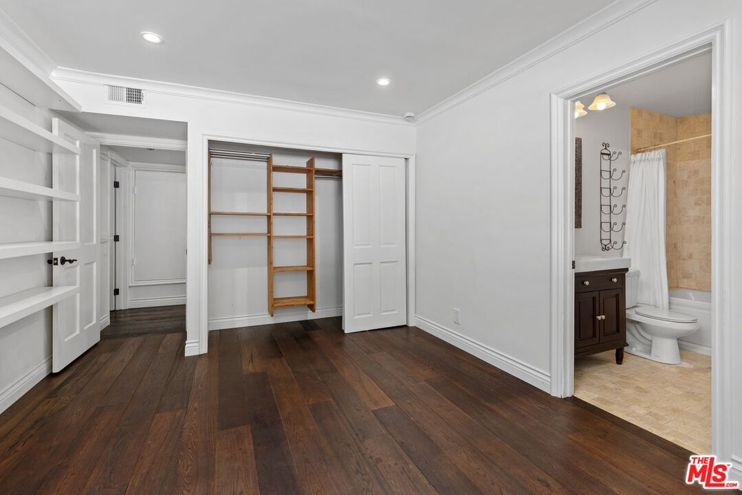 1060 Chantilly Road Los Angeles, CA 90077 - Photo 21 of 40 a view of an empty room with wooden floor and a kitchen