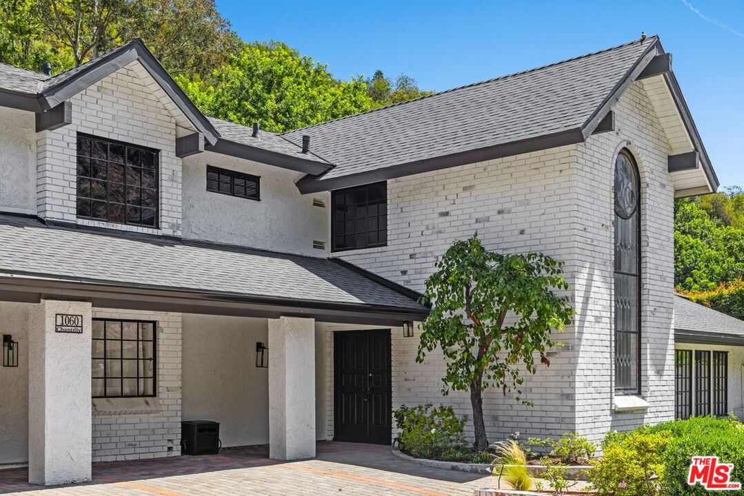 1060 Chantilly Road Los Angeles, CA 90077 - Photo 4 of 40 a view of a white house with potted plants and a table and chairs