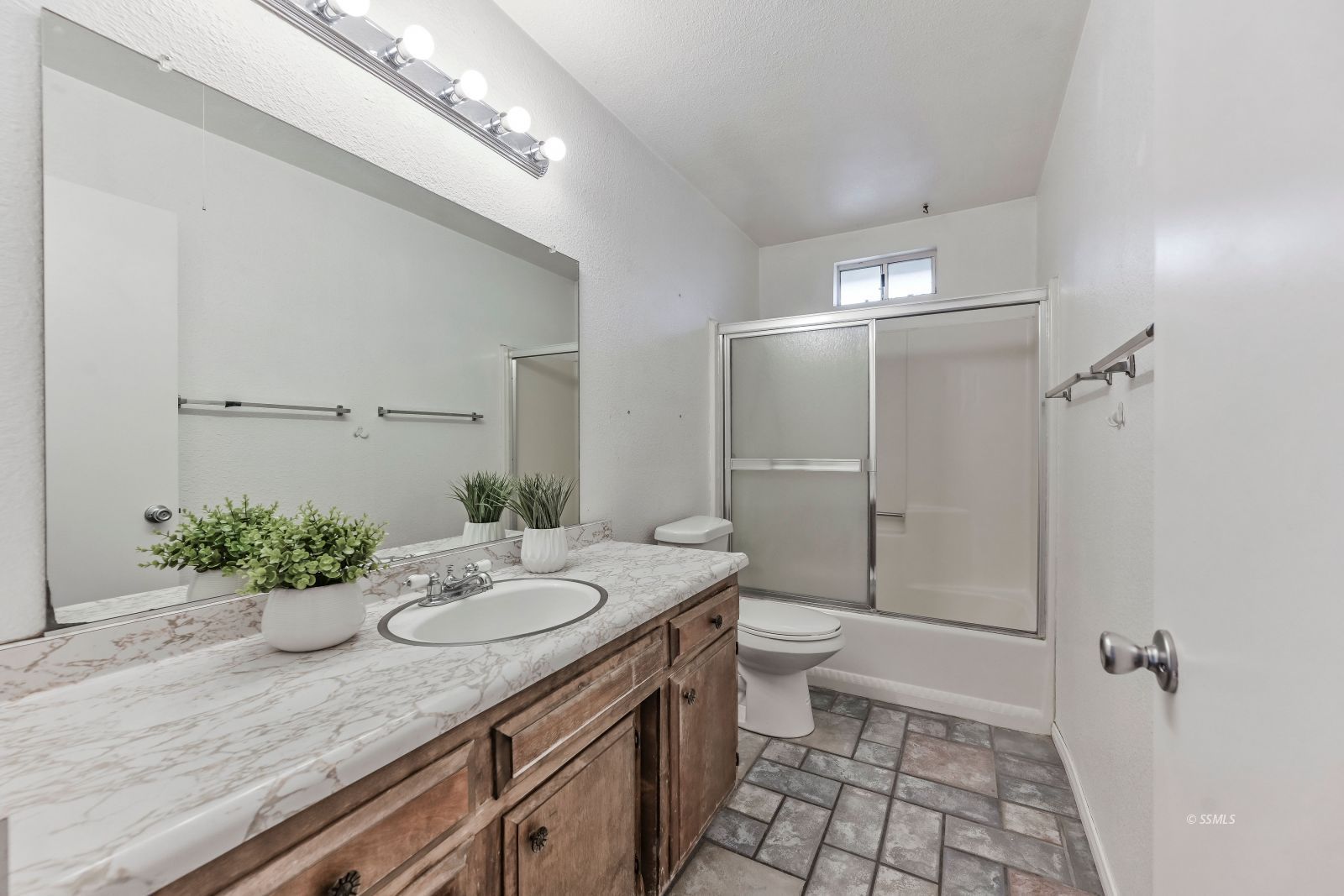 932 West St George Avenue Ridgecrest, CA 93555 - Photo 15 of 28 a bathroom with a granite countertop sink a toilet a mirror and shower