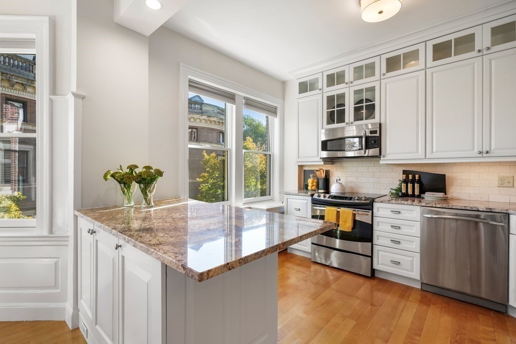 311 Commonwealth Avenue, Unit 41 Boston, MA 02115 - Photo 11 of 31 a kitchen with stainless steel appliances granite countertop a stove a sink and a microwave
