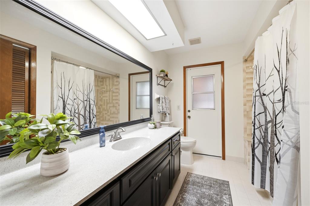 5227 Suwannee Road Weeki Wachee, FL 34607 - Photo 30 of 62 a bathroom with a granite countertop sink a mirror and a shower