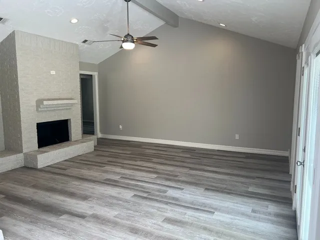 a view of an empty room with a fireplace and a window