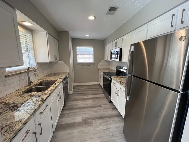 a kitchen with stainless steel appliances granite countertop a refrigerator a stove a sink and a refrigerator