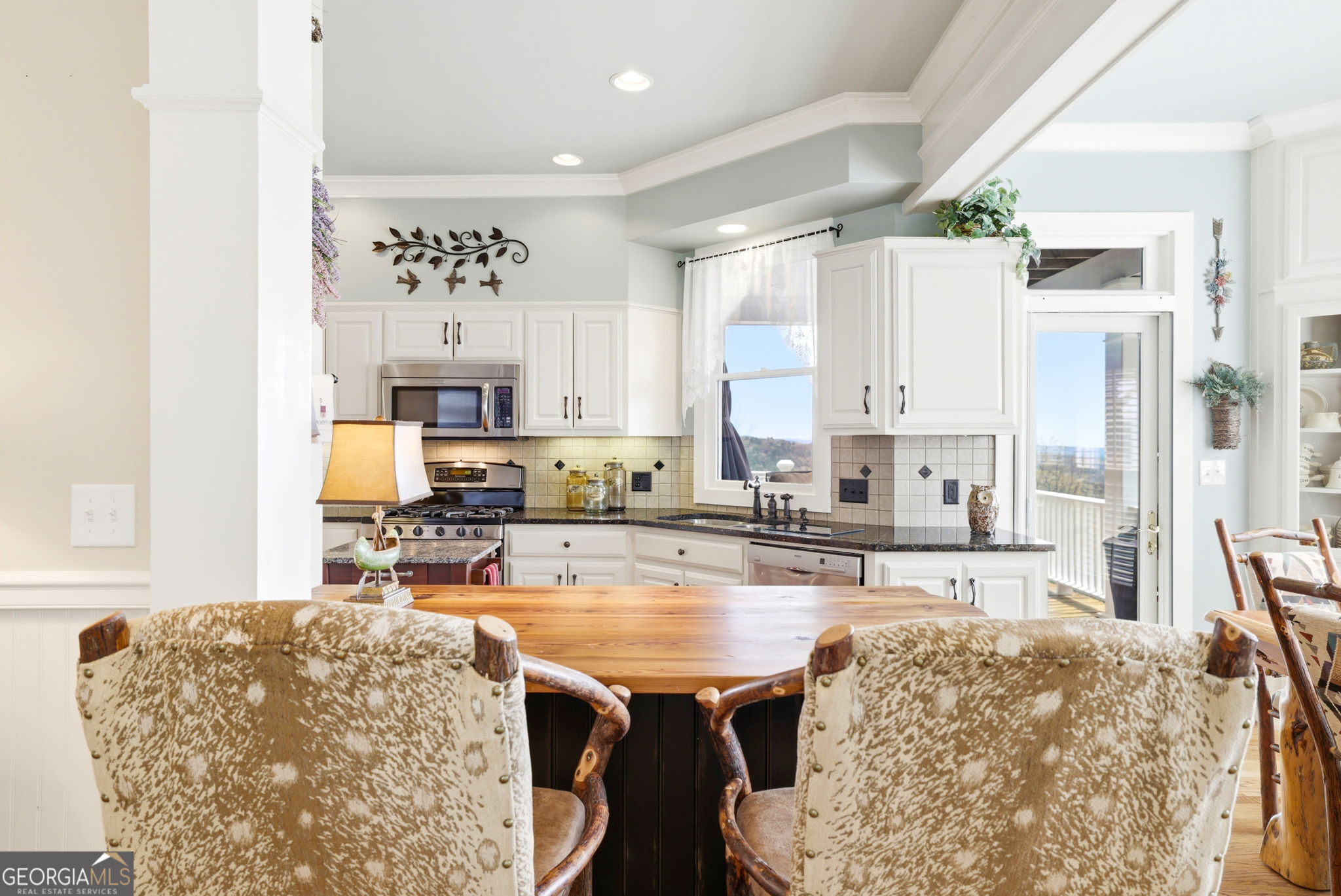 1171 Rabun Bluffs Drive Lakemont, GA 30552 - Photo 12 of 75 a kitchen with stainless steel appliances granite countertop a stove top oven a sink a dining table and chairs with white cabinets