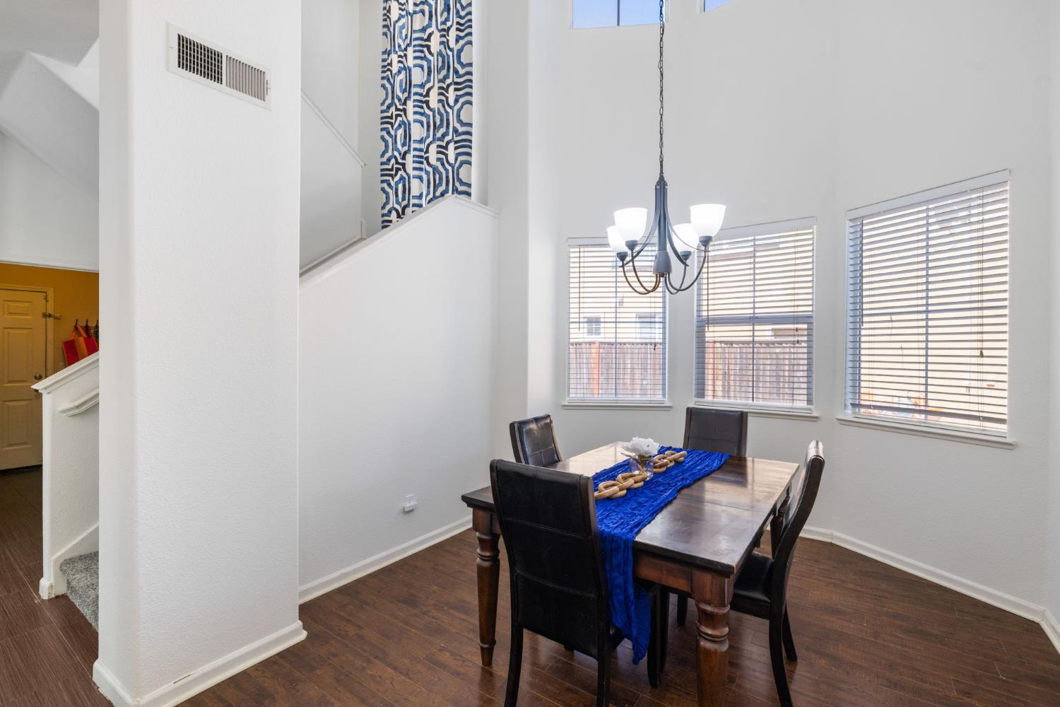562 Ranger Street Oakdale, CA 95361 - Photo 15 of 63 Dining room with dark wood-style floors, chandelier, bay windows, towering ceiling, and stairs