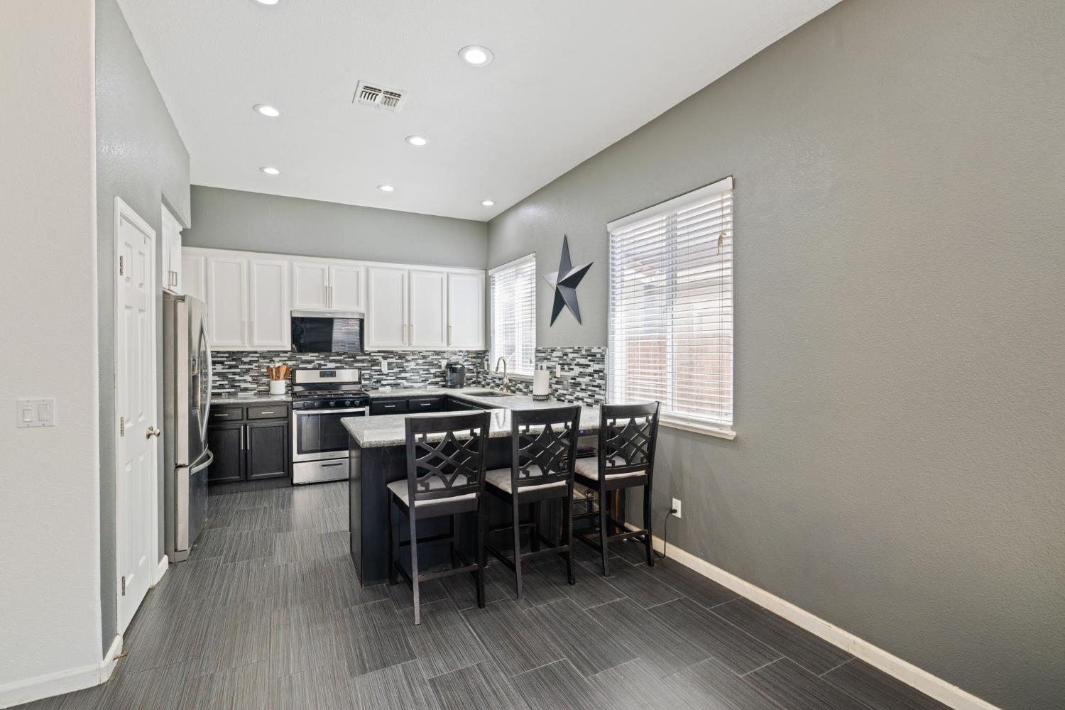 562 Ranger Street Oakdale, CA 95361 - Photo 23 of 63 kitchen featuring white cabinets, appliances with stainless steel finishes, decorative backsplash, a breakfast bar, and a peninsula