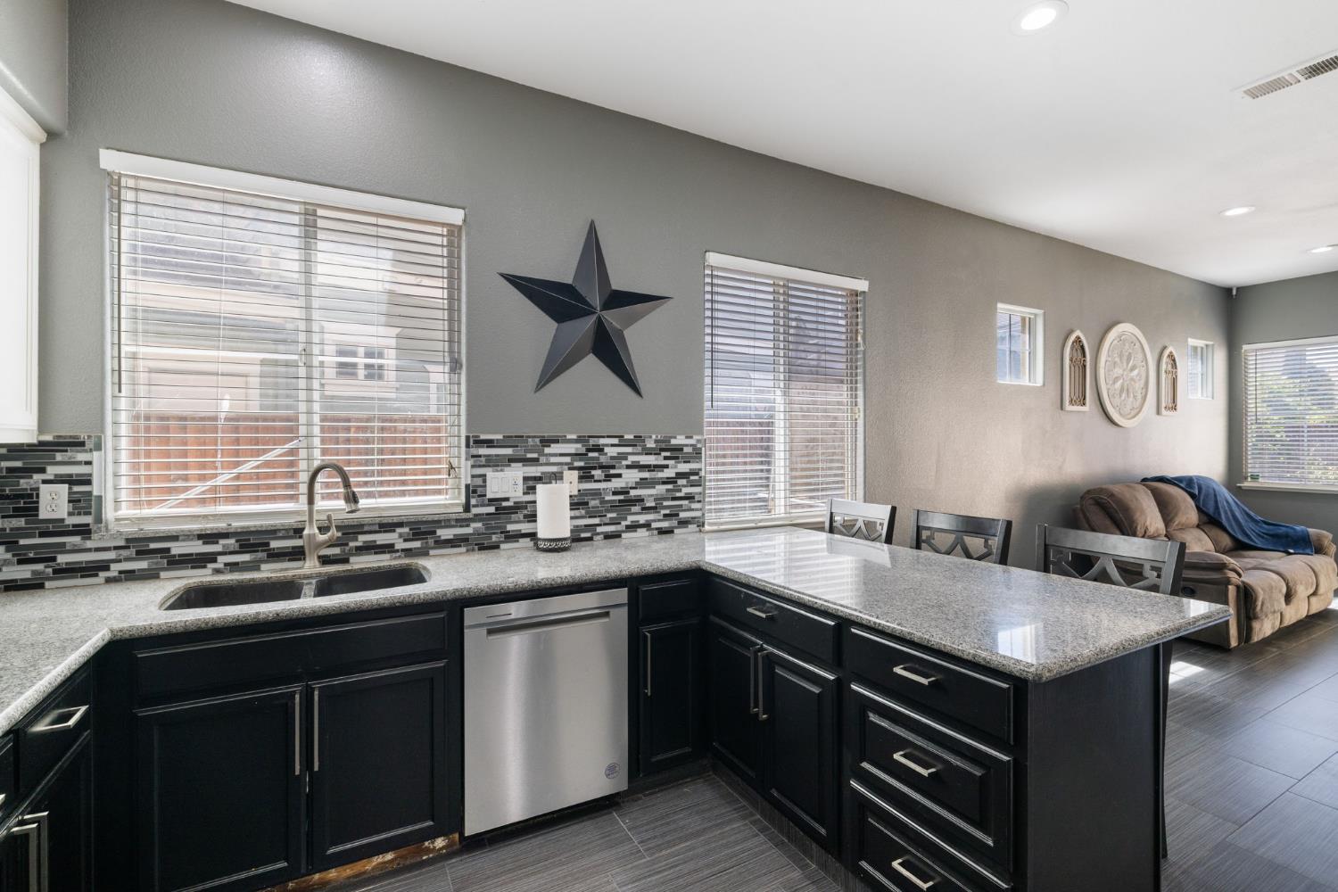 562 Ranger Street Oakdale, CA 95361 - Photo 26 of 63 kitchen featuring dark cabinetry, a peninsula, stainless steel dishwasher, granite countertops and family room combo