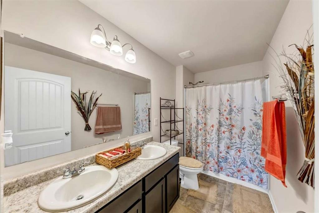 3737 Makeover Court Atlanta, GA 30349 - Photo 24 of 34 a bathroom with a granite countertop sink a toilet a mirror and shower