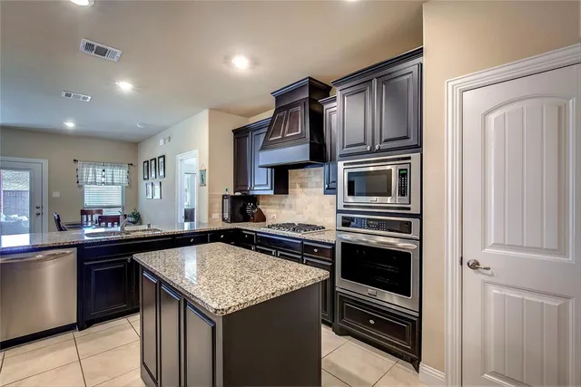 a kitchen with granite countertop a refrigerator and a stove top oven