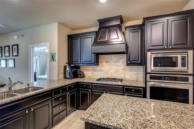 a kitchen with granite countertop a sink stove and refrigerator