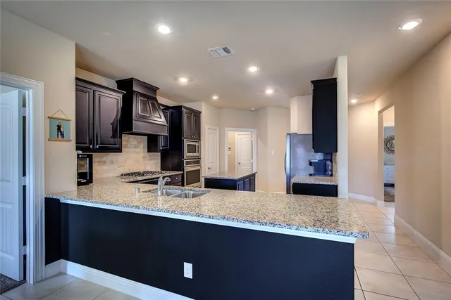 a large kitchen with granite countertop a large counter top stainless steel appliances and cabinets
