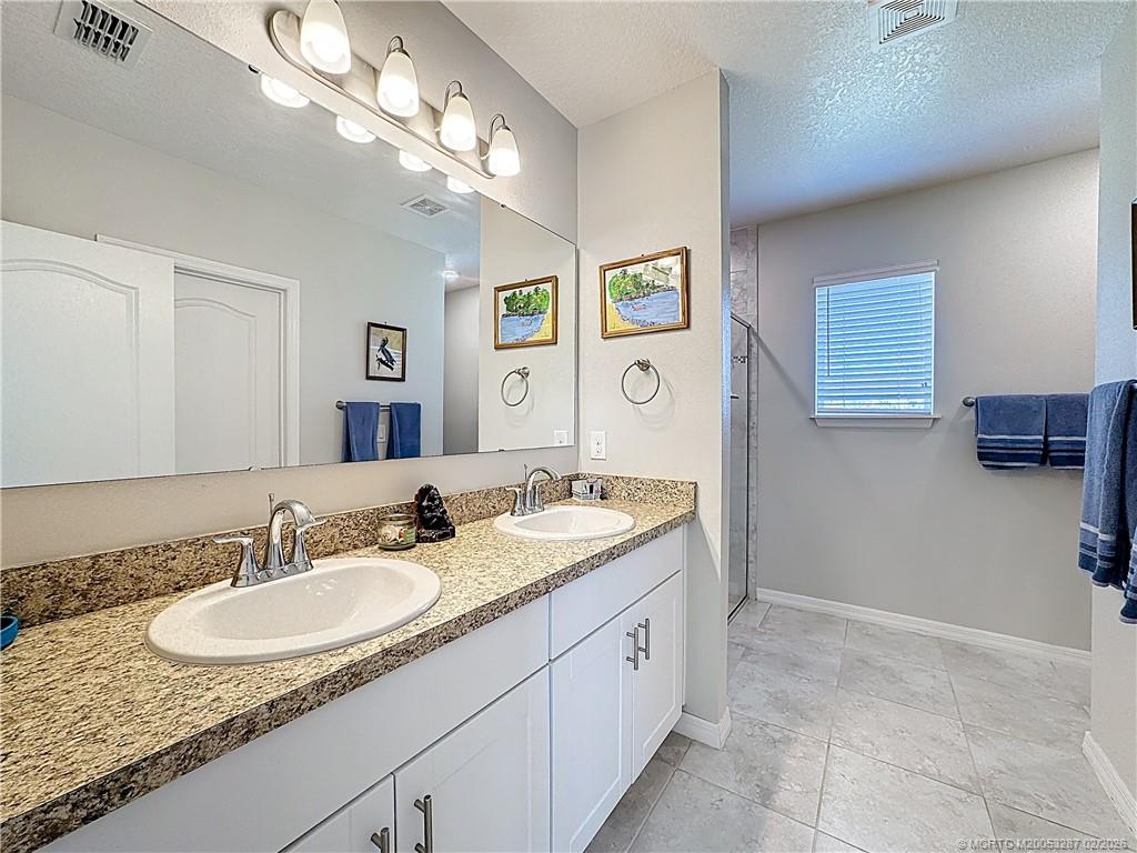 4341 Southwest Appleseed Road Port St. Lucie, FL 34953 - Photo 8 of 25 a bathroom with a granite countertop sink a mirror and shower