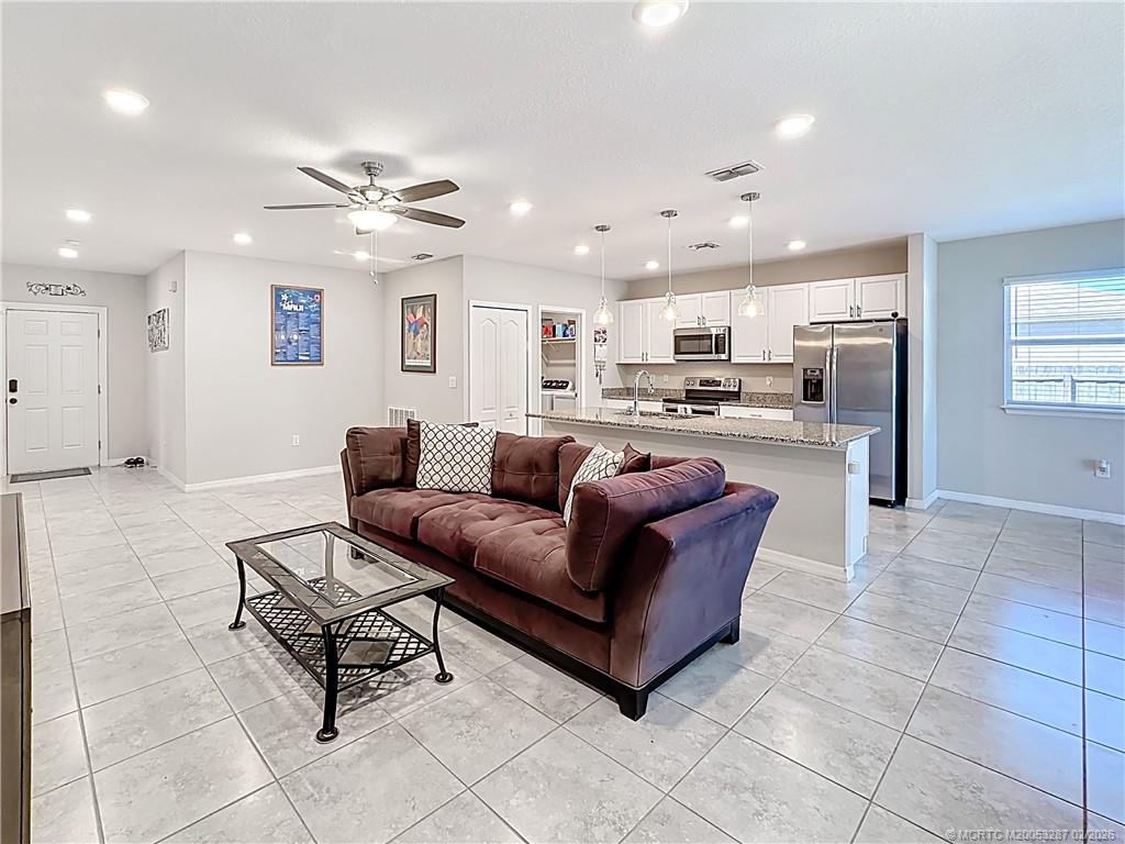 4341 Southwest Appleseed Road Port St. Lucie, FL 34953 - Photo 2 of 25 a living room with stainless steel appliances furniture a rug and a view of kitchen