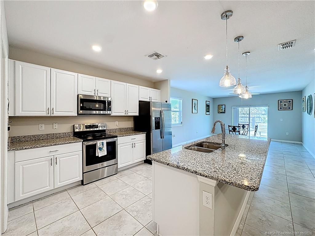4341 Southwest Appleseed Road Port St. Lucie, FL 34953 - Photo 22 of 25 a kitchen with kitchen island granite countertop a stove sink and cabinets
