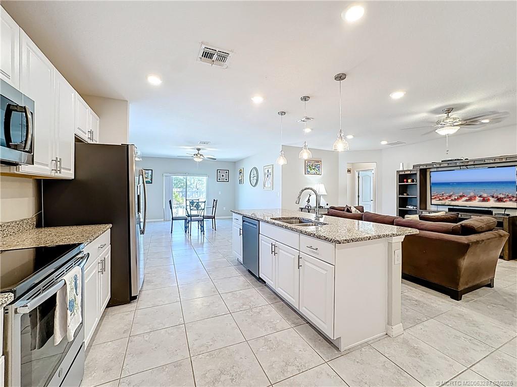 4341 Southwest Appleseed Road Port St. Lucie, FL 34953 - Photo 3 of 25 a kitchen with stainless steel appliances granite countertop a refrigerator and a stove top oven