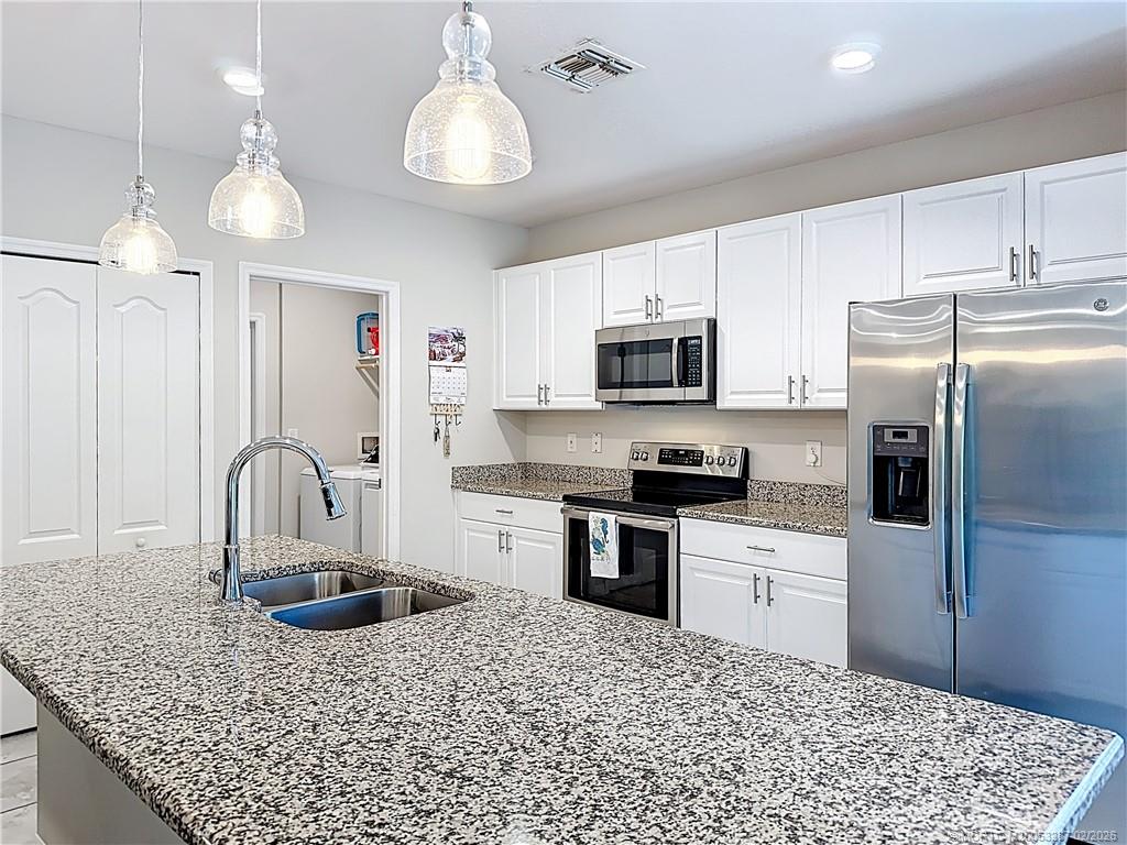 4341 Southwest Appleseed Road Port St. Lucie, FL 34953 - Photo 23 of 25 a kitchen with stainless steel appliances granite countertop a sink a stove a refrigerator cabinets a dining table and chairs