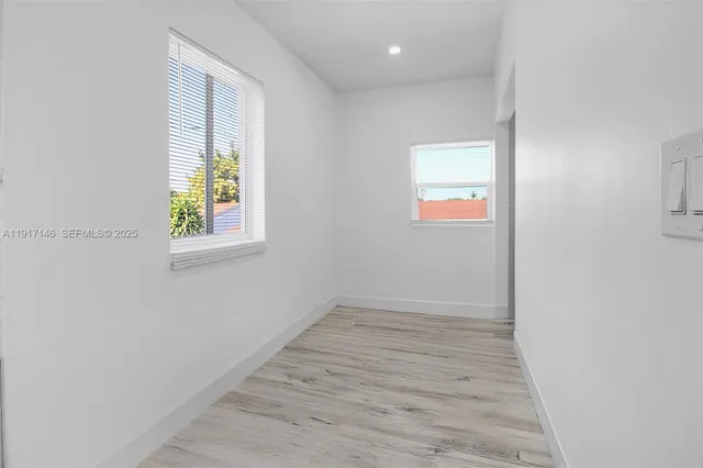 an empty room with windows and wooden floor