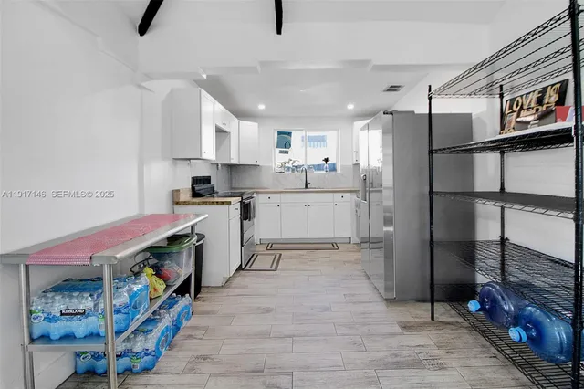 a kitchen with stainless steel appliances granite countertop a refrigerator a stove a sink dishwasher and white cabinets with wooden floor