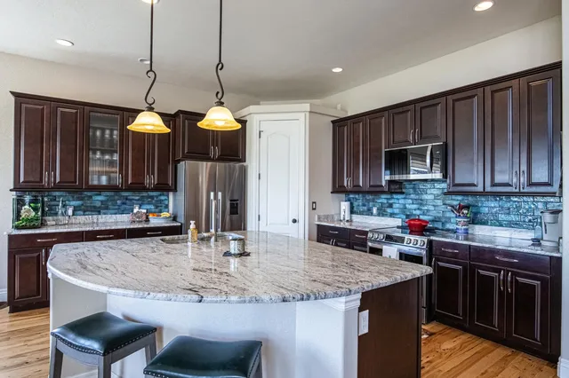 a kitchen with kitchen island granite countertop a sink a counter top space appliances and cabinets