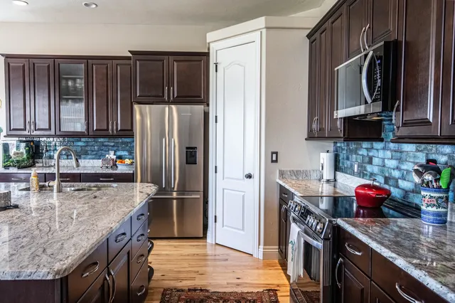 a kitchen with granite countertop a refrigerator stove and microwave