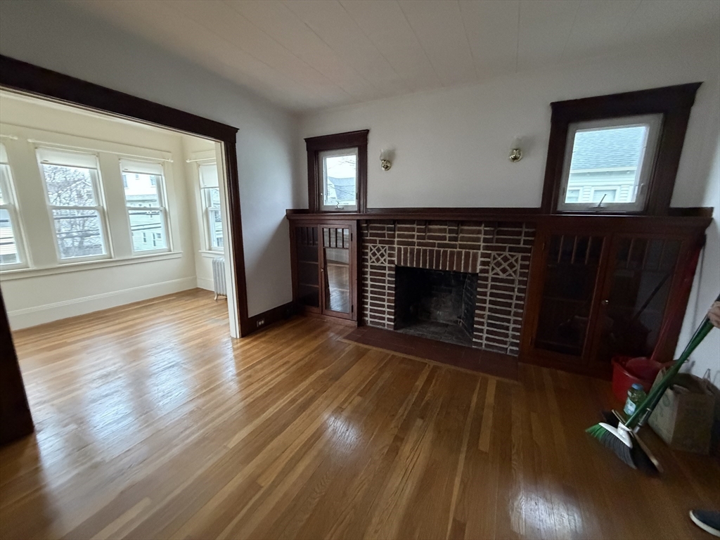 44 Varnum Street, Unit 2 Arlington, MA 02474 - Photo 4 of 19 a view of an empty room with wooden floor and a fireplace