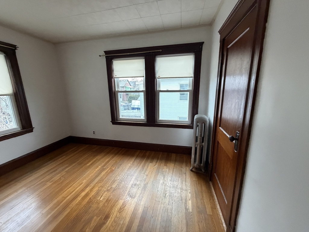 44 Varnum Street, Unit 2 Arlington, MA 02474 - Photo 10 of 19 an empty room with wooden floor and windows