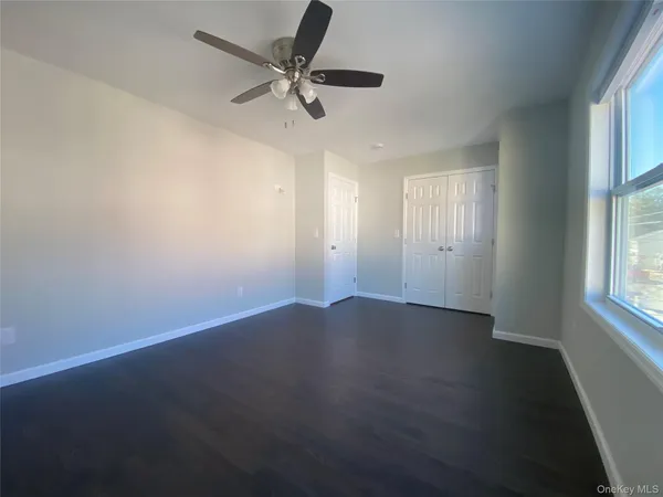 an empty room with wooden floor fan and windows