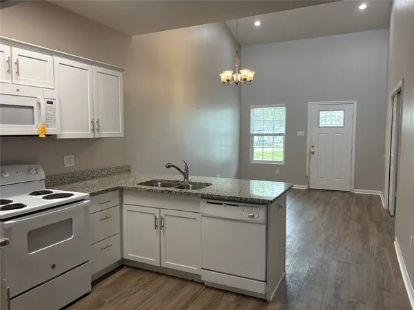 a kitchen with granite countertop stainless steel appliances a stove cabinets and wooden floor