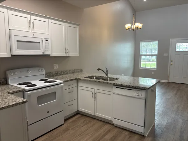 a kitchen with granite countertop a sink a stove and cabinets