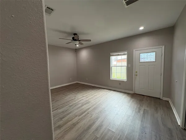 an empty room with wooden floor and windows
