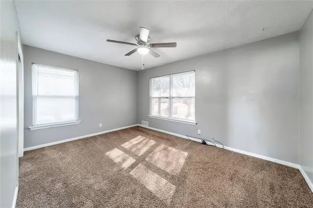 an empty room with windows and ceiling fan