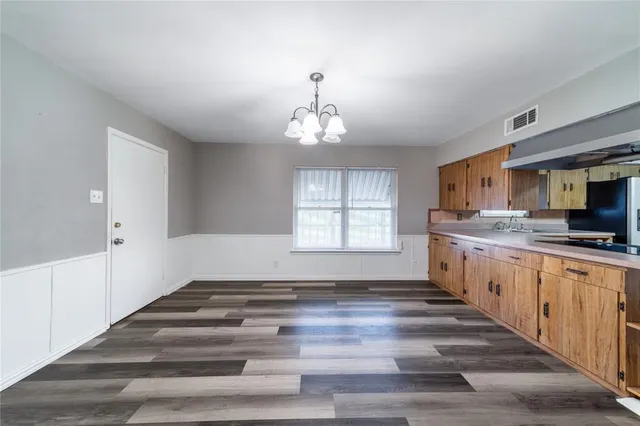 a large white kitchen with granite countertop a sink dishwasher a stove and a refrigerator