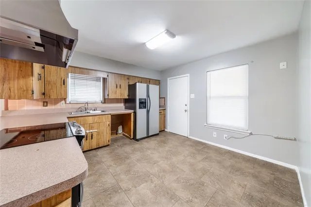 a kitchen with granite countertop a refrigerator a sink dishwasher and white cabinets with wooden floor