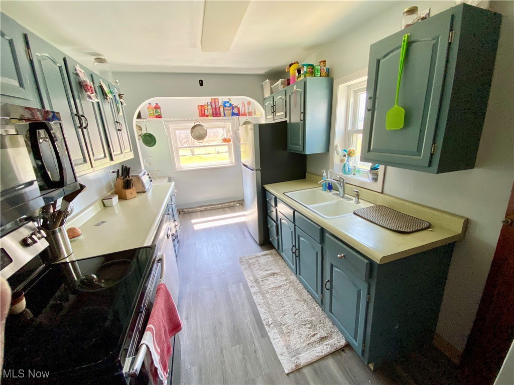 4246 South Ridge Road Perry, OH 44081 - Photo 2 of 13 Kitchen featuring light countertops, stainless steel electric range, a sink, black microwave, and wood finished floors