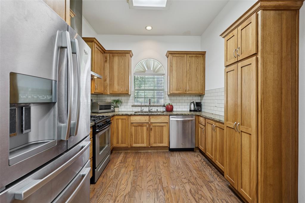 3004 Springfellow Drive Plano, TX 75025 - Photo 13 of 37 a kitchen with stainless steel appliances granite countertop a refrigerator a sink dishwasher a stove and white countertops with wooden floor