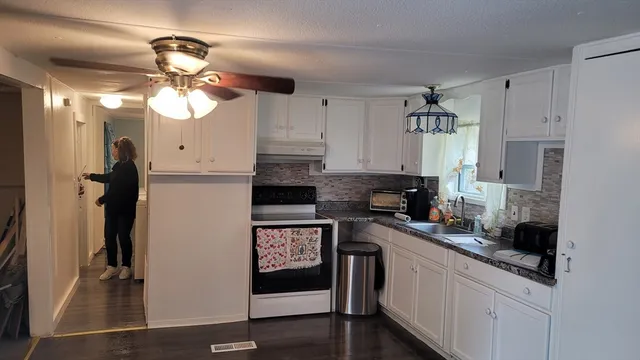 a kitchen with stainless steel appliances granite countertop a refrigerator a sink a stove and white cabinets